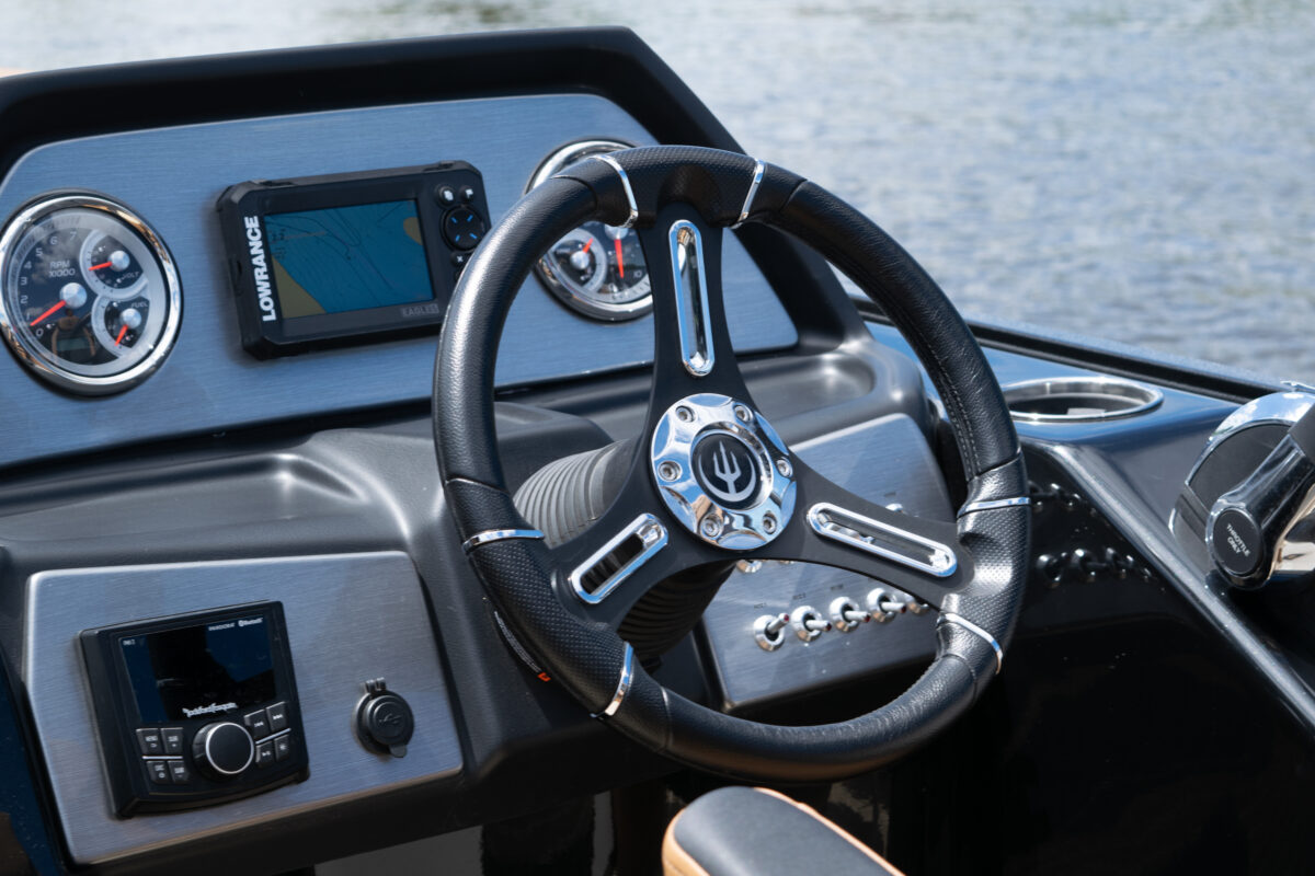 view of steering wheel on the red and white tritoon